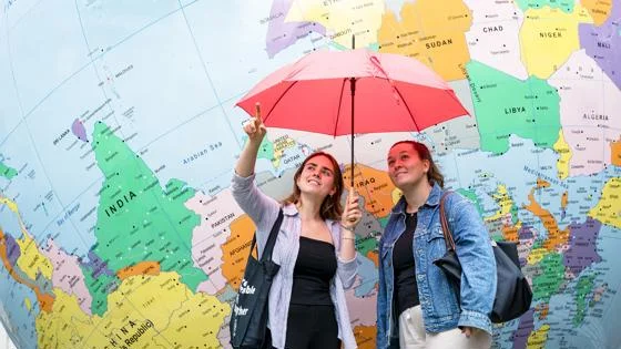 two women stand in front of LSE globe