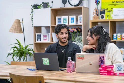 LSE students sitting together on campus with laptops