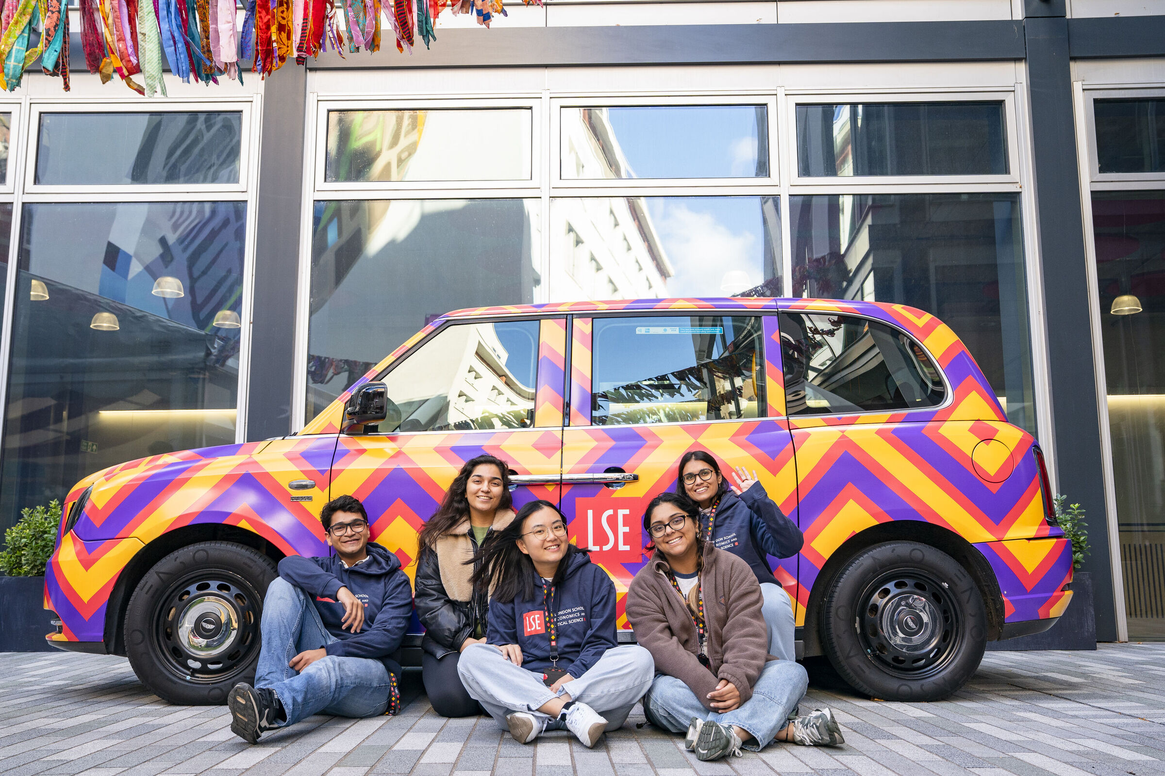 Five students by LSE branded taxi