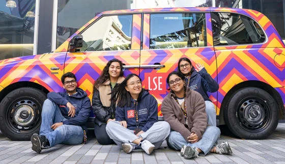 Five students by LSE branded taxi