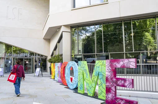 Student with LSE tote bag walking past letters spelling out WELCOME on the LSE campus.