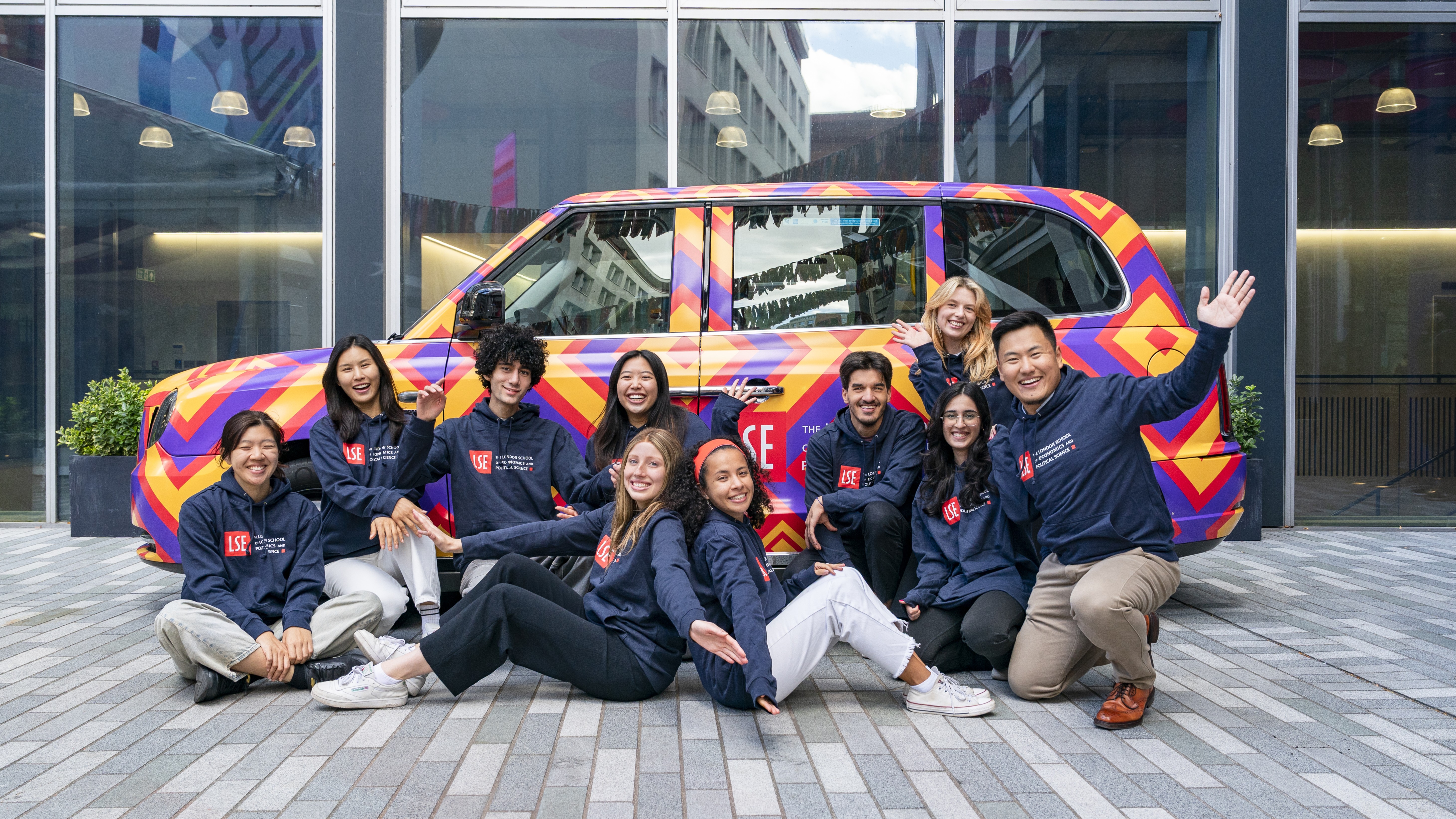LSE students next to a brightly coloured car