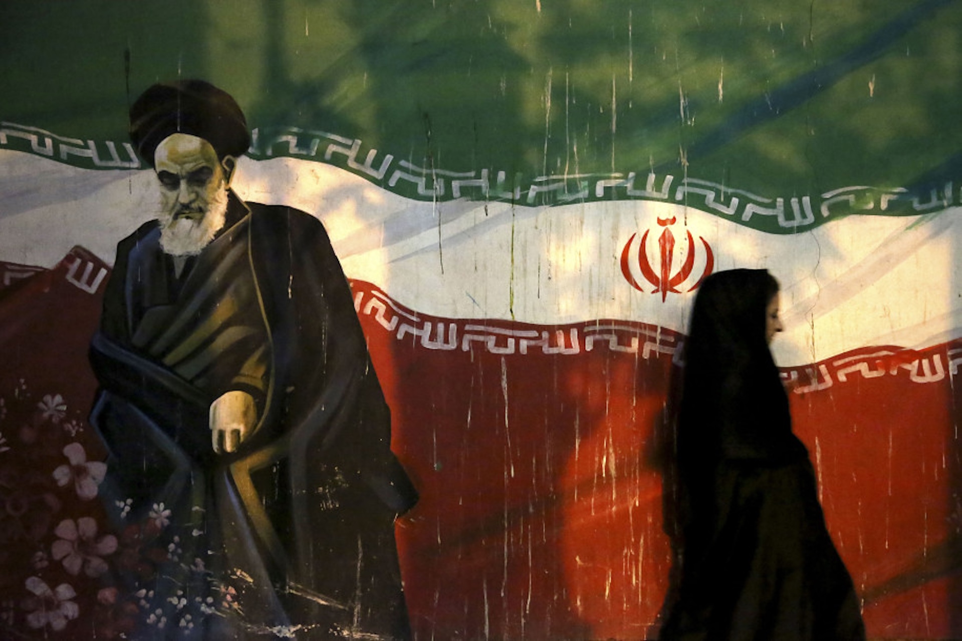 A woman walks past a mural of Ayatollah Ruhollah Khomeini in Tehran. Source: Michael Lloyd, Flickr, CC by 2.0