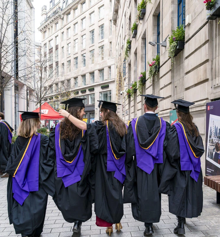 Graduation ceremony on LSE campus featuring LSE students in caps and gowns walking through Houghton Street