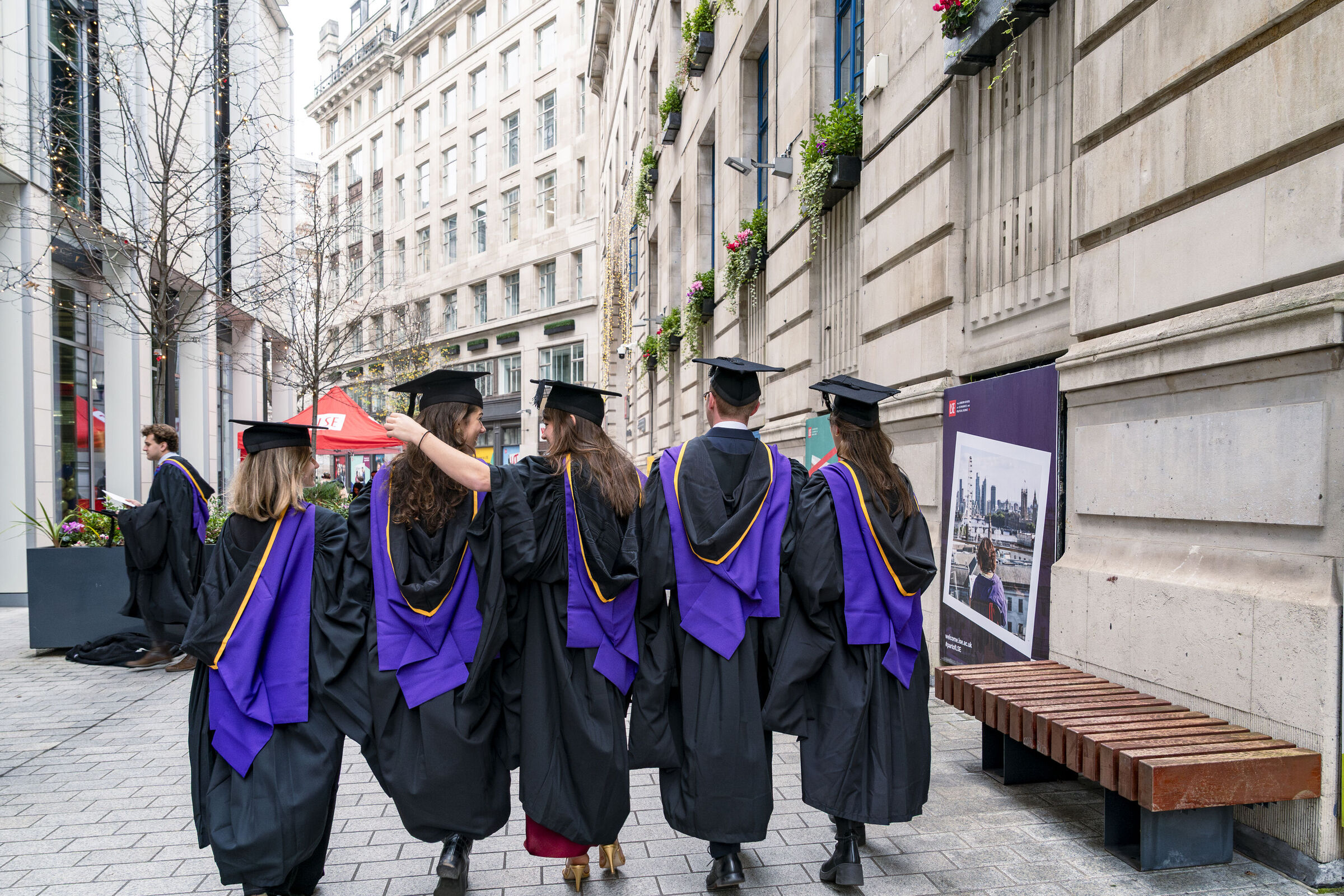 Graduation ceremony on LSE campus featuring LSE students in caps and gowns walking through Houghton Street
