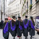 Graduation ceremony on LSE campus featuring LSE students in caps and gowns walking through Houghton Street