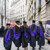Graduation ceremony on LSE campus featuring LSE students in caps and gowns walking through Houghton Street