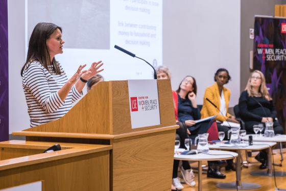 Speaker presenting with other three speakers on stage