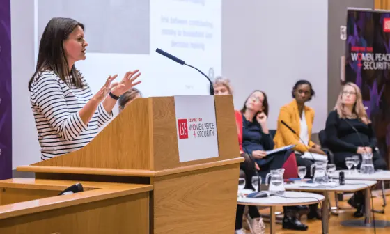 Speaker presenting with other three speakers on stage