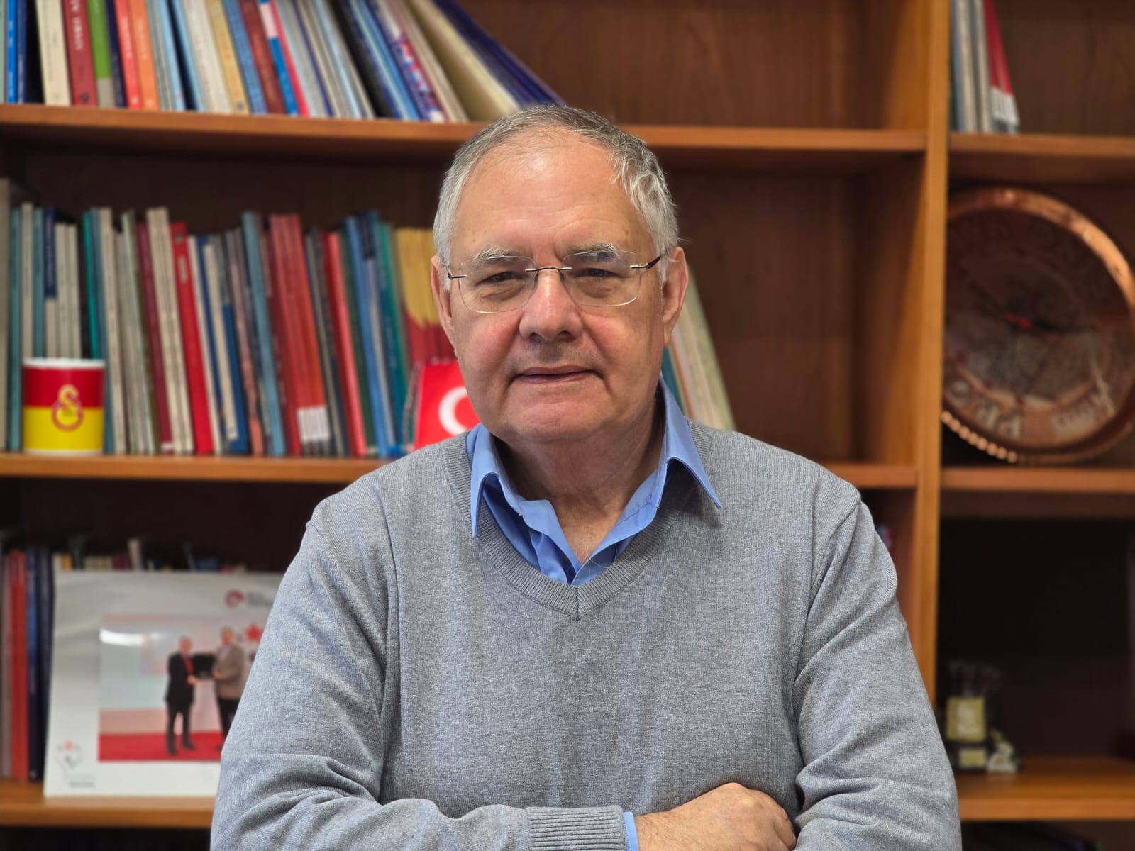Man standing in front of a bookcase with arms folded