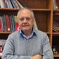 Man standing in front of a bookcase with arms folded
