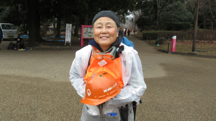 Naomi Tobita stands outside of Kanagawa Forest holding an orange helmet