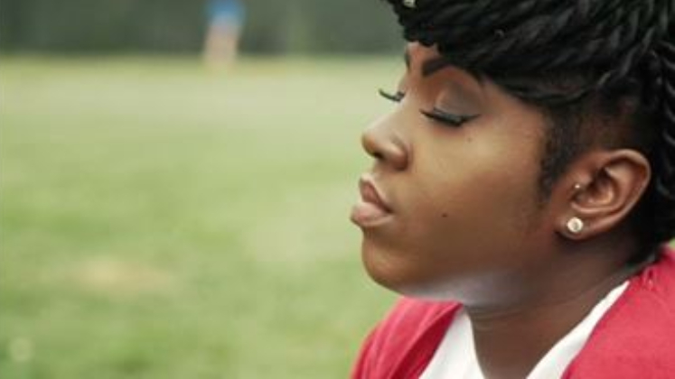 A Black teenage girl sits in a park