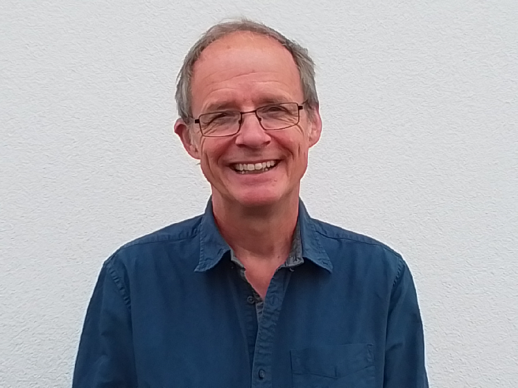 Profile image of Nick Louth showing him wearing a dark blue shirt and standing against a white wall