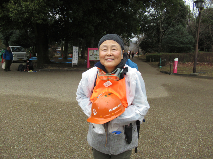 Naomi Tobita stands outside of Kanagawa Forest holding her orange volunteer helmet.