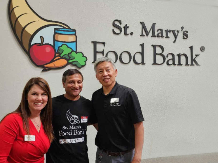 Rasik Mistry stands in between two other volunteers outside of St Mary's Food Bank in Arizona