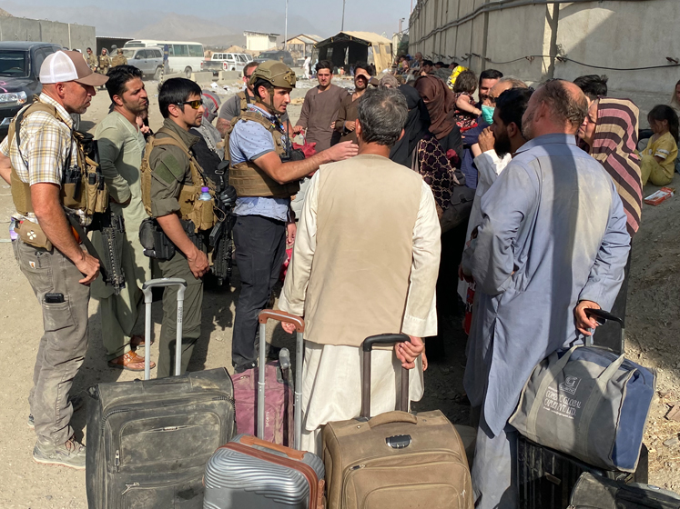 Samuel Aronson stands in the centre of a group of Afghan evacuees explaining something