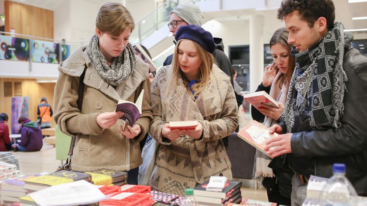Two woman and one man look at books during a book sale in LSE's CKK building