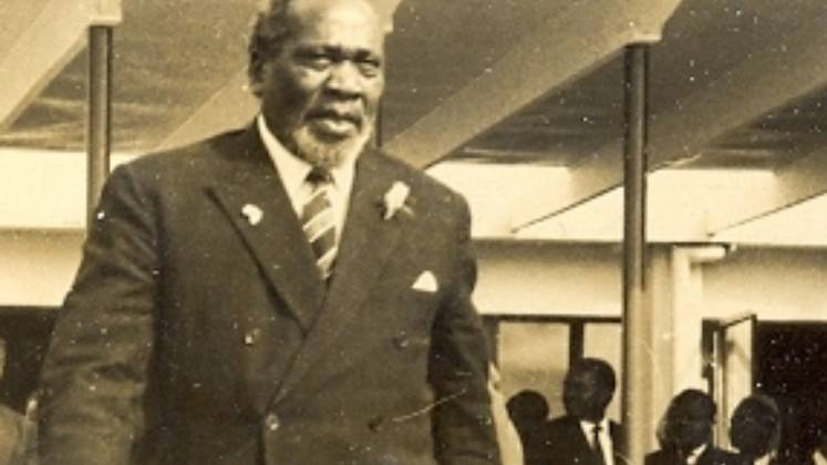 Black and white photo of Jomo Kenyatta walking through a building