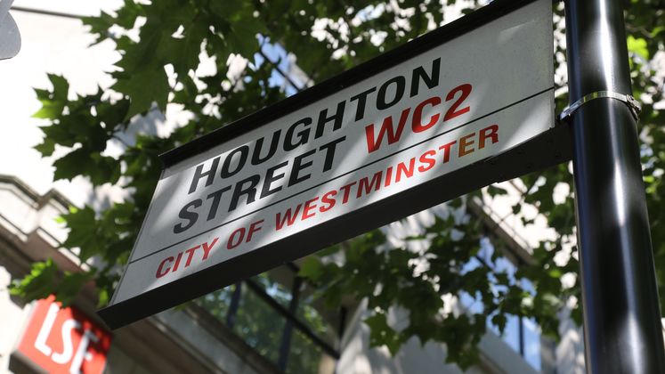 A street sign below some trees says 'Houghton Street'