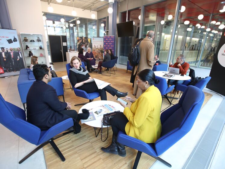 Three people sit and chat at a coffee table in the LSE Alumni Centre