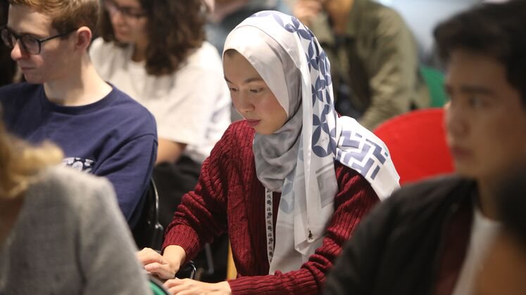 A woman wearing a hijab uses a laptop in an LSE lecture