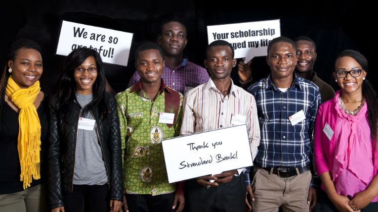 A group of people holding up placards that say 'thank you Standard Bank'