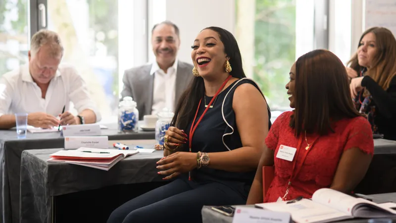 A woman sitting in a classroom laughing  Corporate Finance and Strategy