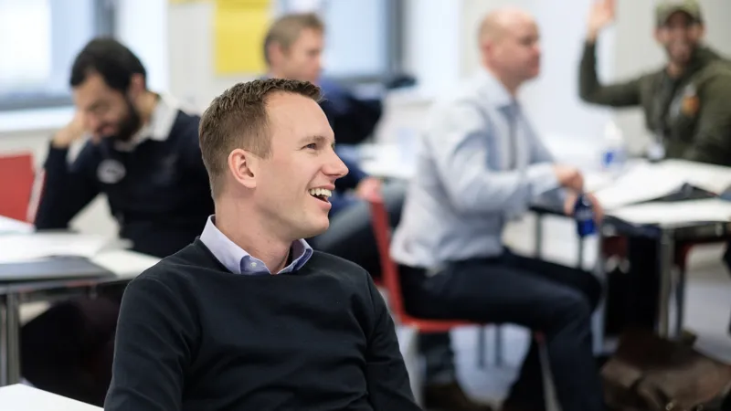 A man sitting in a classroom smiling  Effective Asset Management