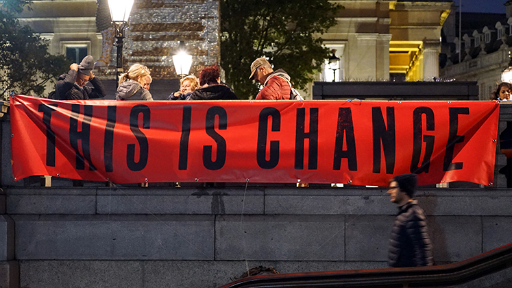 A banner at a protest which reads, "This Is Change".