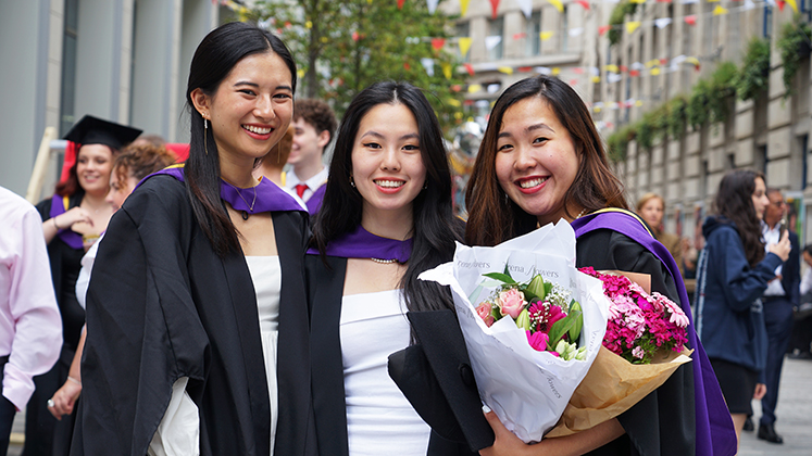 Three graduates celebrate on graduation day.