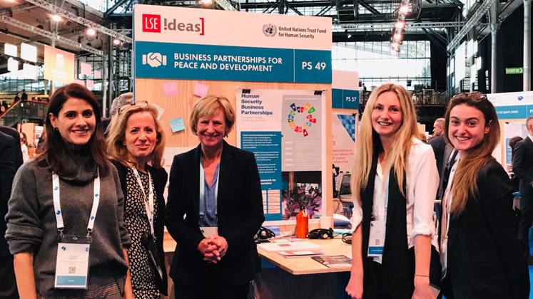 A photo of 5 women next to a project poster and board