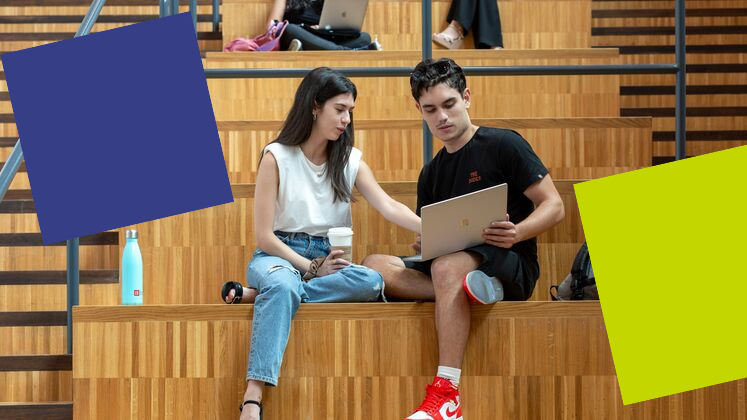 Two students sat on steps at LSE, both looking at a computer