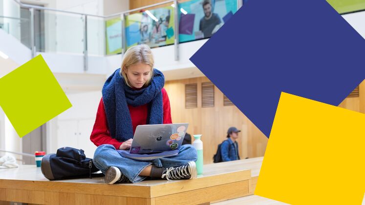 student crosslegged with laptop and scarf