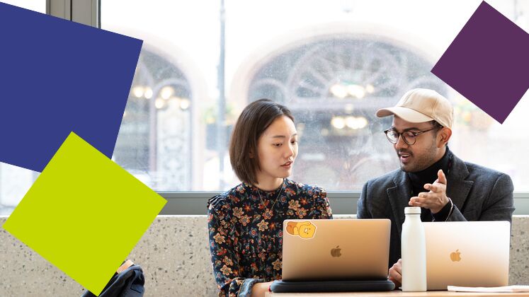 two students with laptops talking