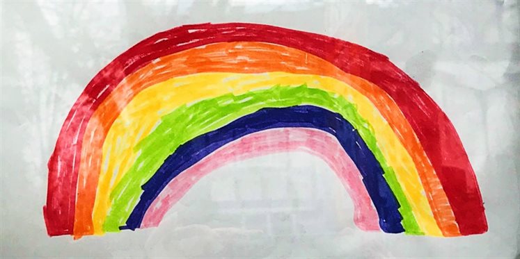 A hand drawn rainbow on the inside of a window