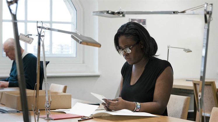 People sitting in the archives reading room using material.