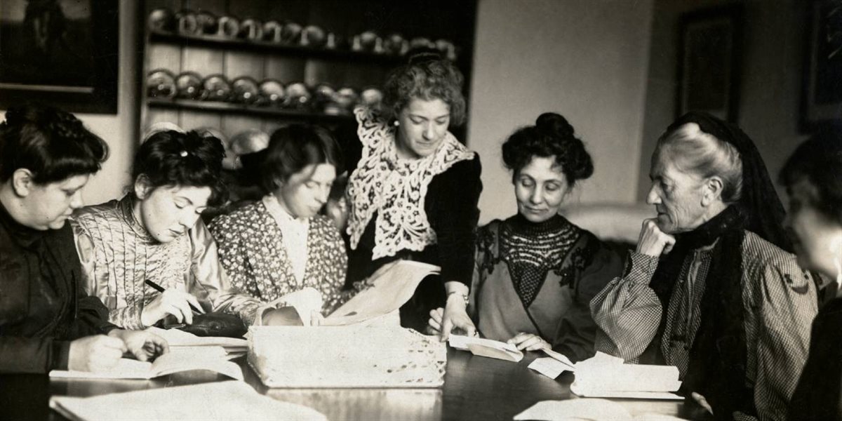 WSPU leaders sitting around a table looking at papers together and writing.