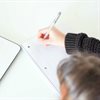 A person taking notes while looking at a computer