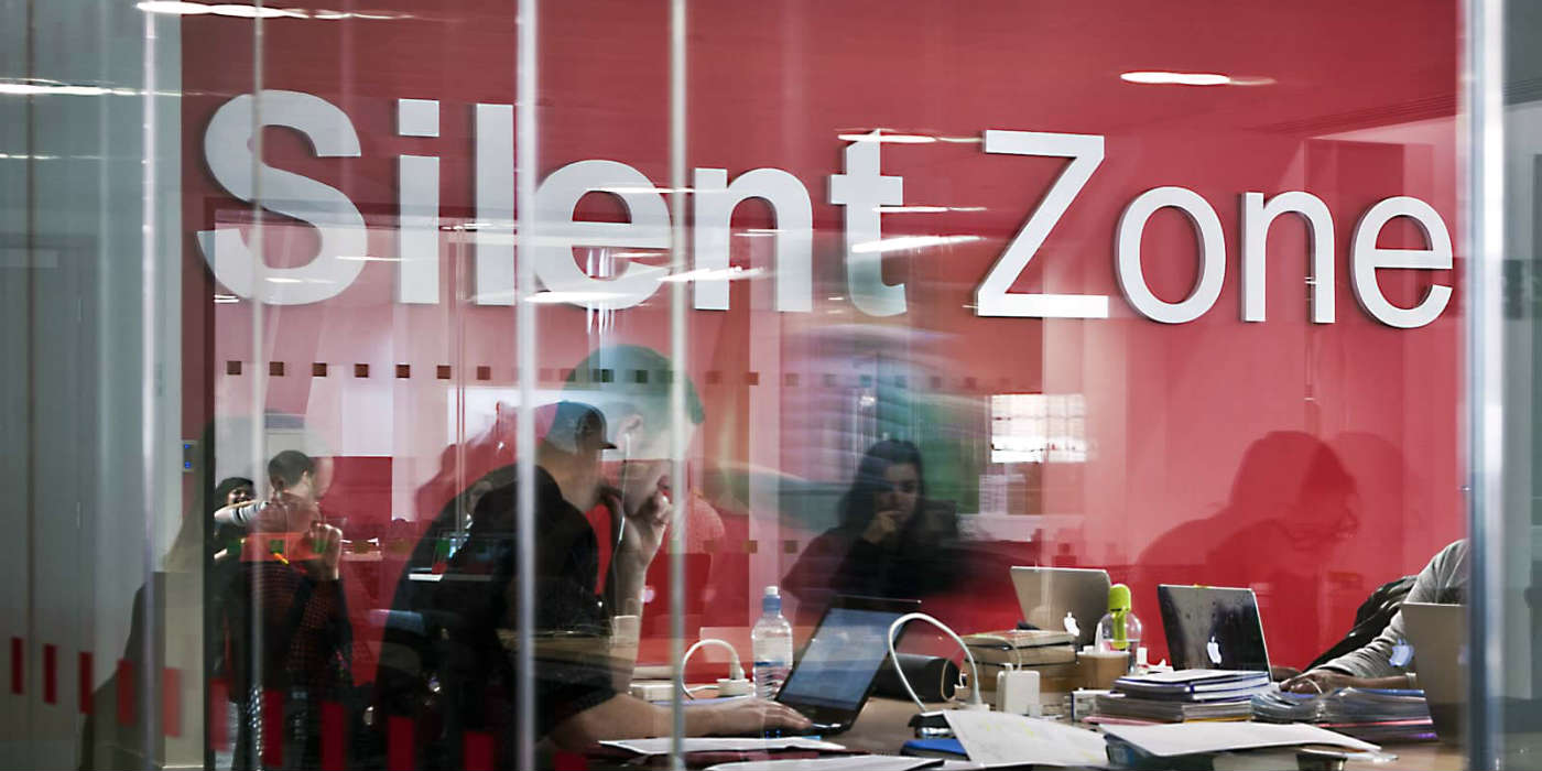 Students in the Silent Zone working with a big sign behind them against a red wall.