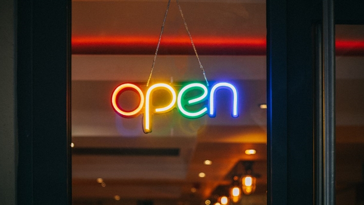 An Open sign hanging in a window. The letters are lit up in rainbow colors