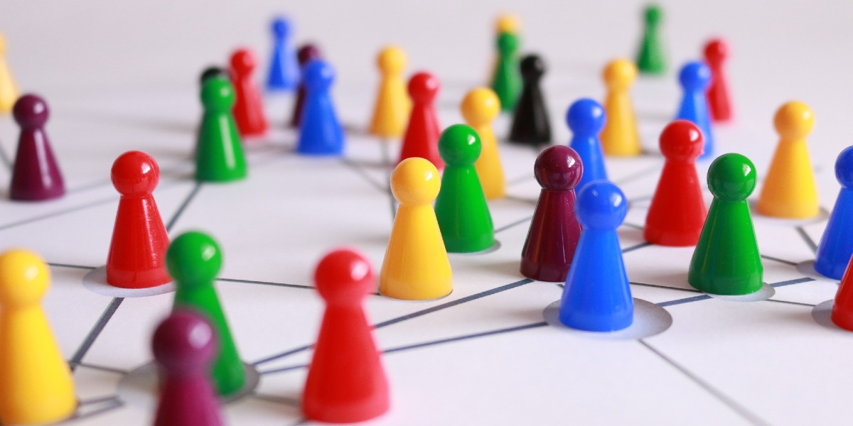 Multi-coloured board games pieces arranged on a board to represent networks