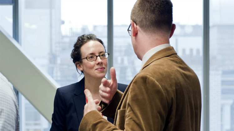 Two people standing up and discussing something.