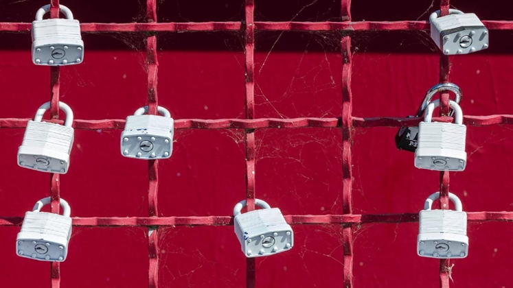 A red metal fence with many white padlocks attached to it