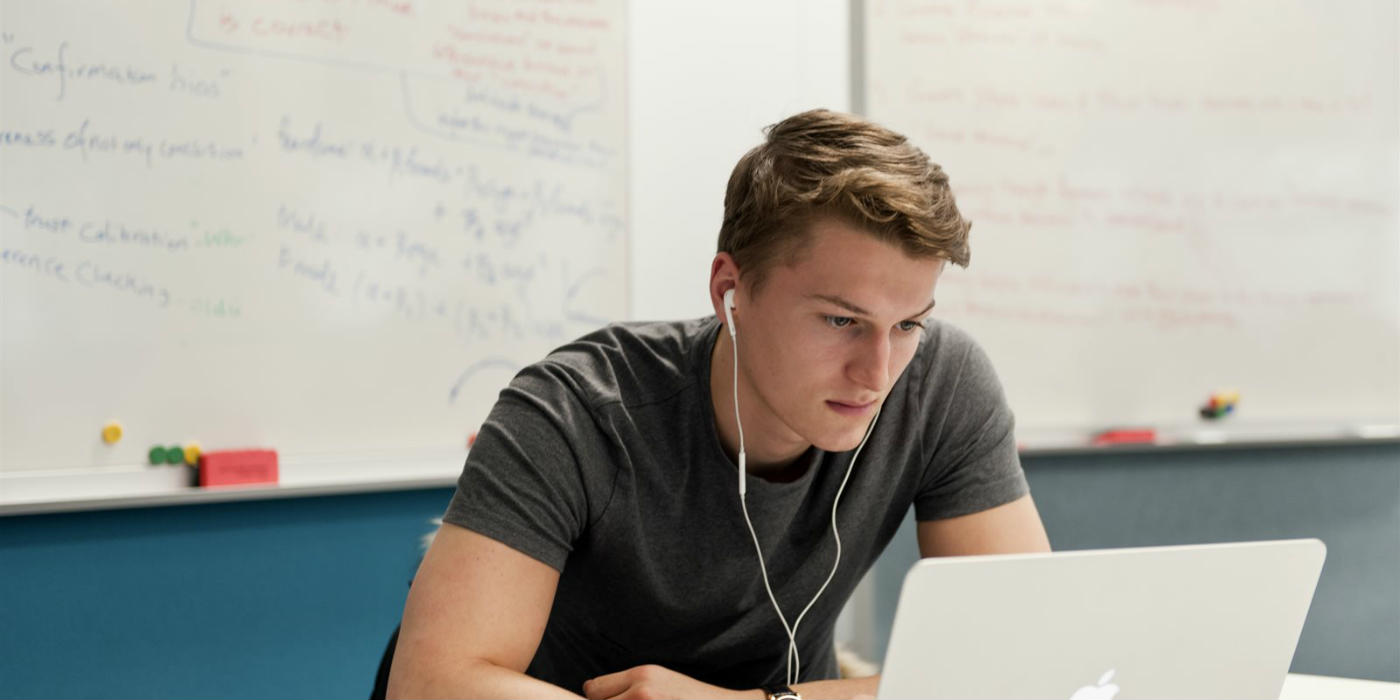 A student sitting down working at a laptop.