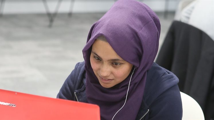 A student working on a laptop at a table.