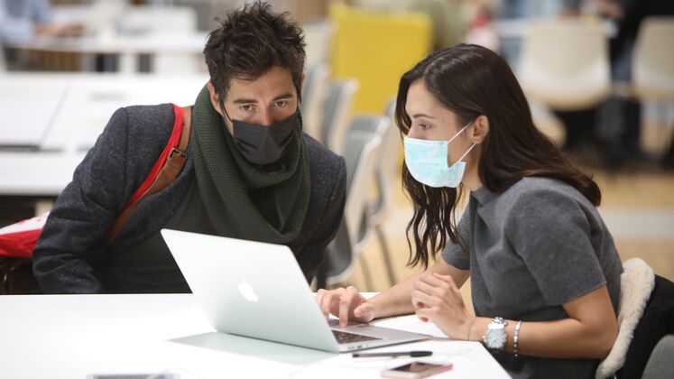 students in masks sat together at a laptop