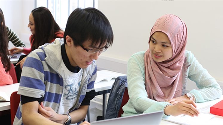 Two students, one male and one female, working together at a desk.