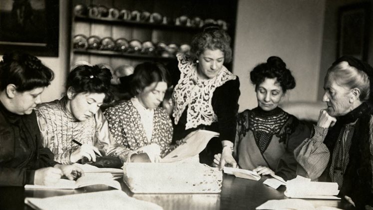 WSPU leaders sitting around a table looking at papers together and writing.