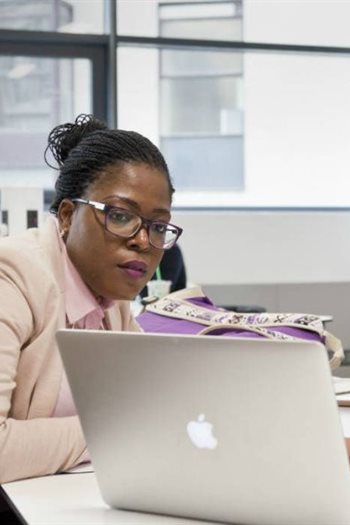 Three students sat together looking at a laptop